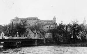 Colditz Castle from the opposite bank of the Mulde River, with the town's road bridge in the foreground. (IWM)